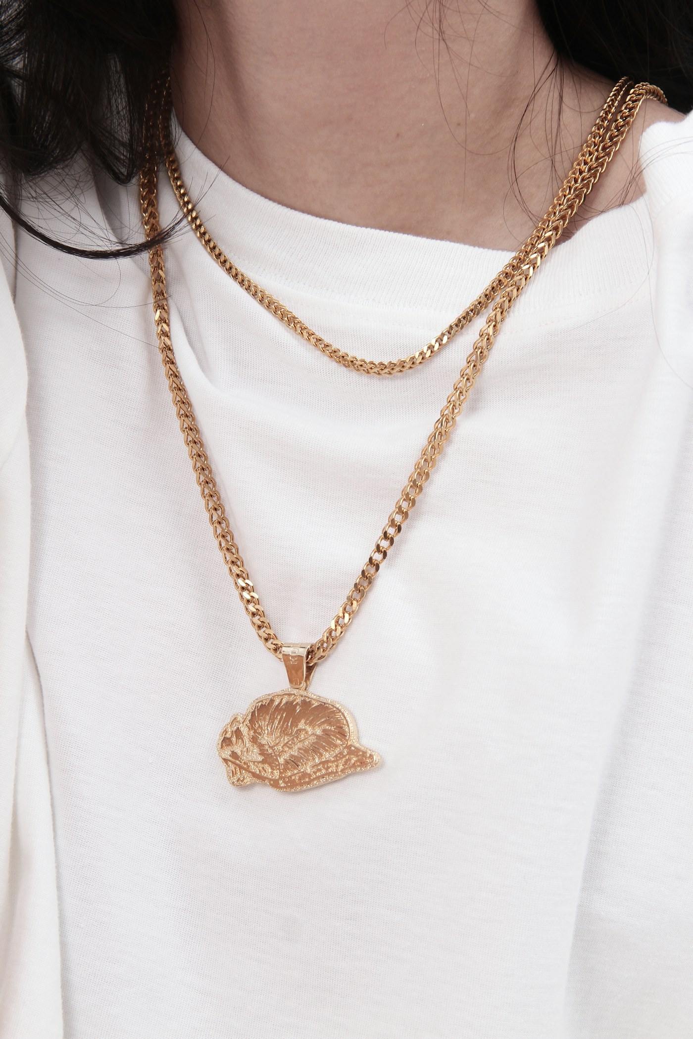 Layered gold-tone necklaces styled over a white shirt