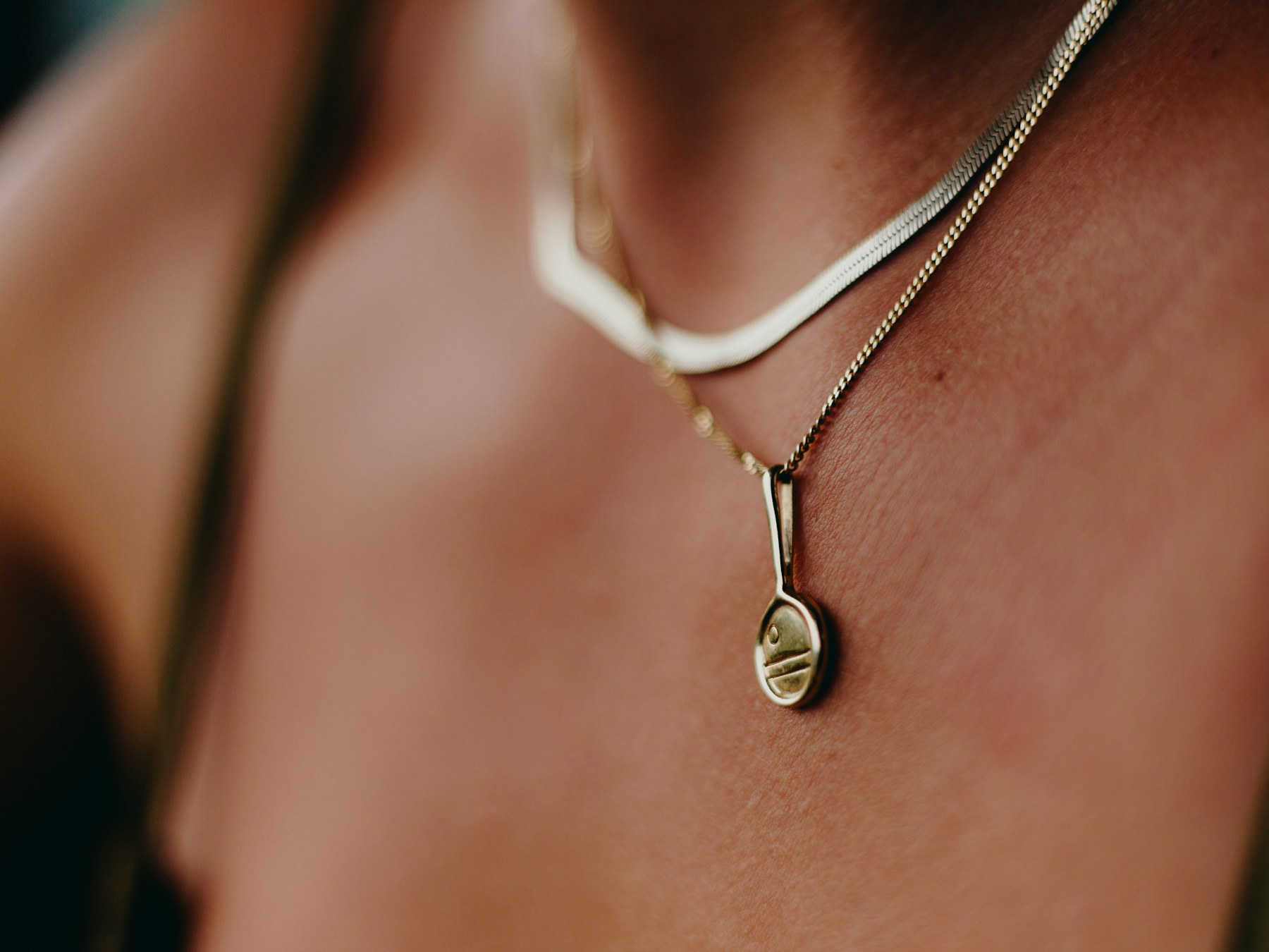 Woman wearing a delicate gold necklace in warm light